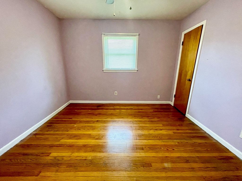 a empty room with wooden floors and a window and a door