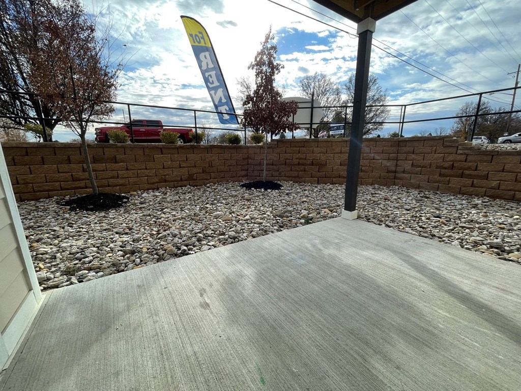 a view of the patio of a building with gravel and a fence