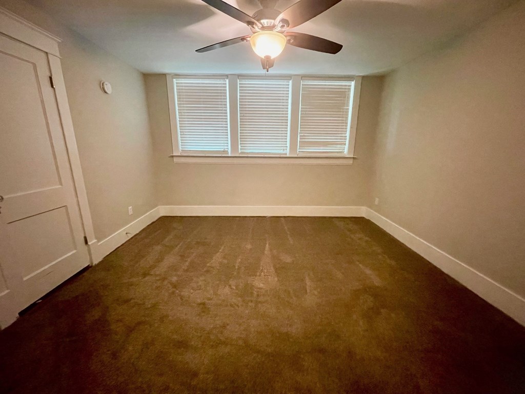 a empty room with a ceiling fan and a window