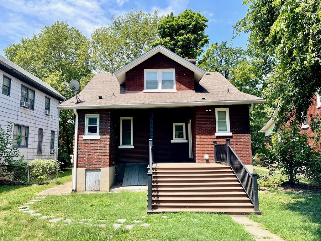 a small brick house with a porch and stairs