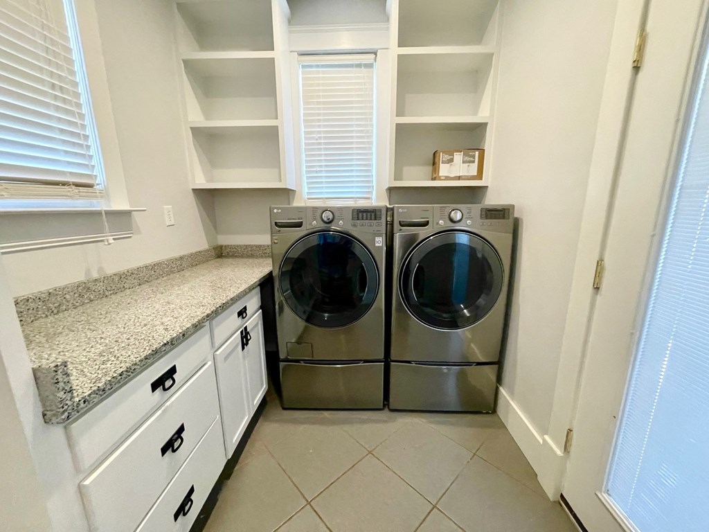 a washer and dryer in a laundry room with white cabinets