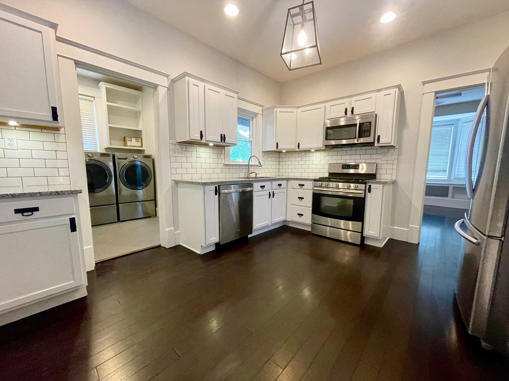 a kitchen with white cabinets and stainless steel appliances