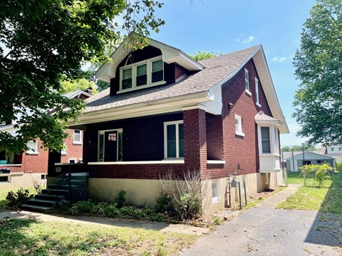 a red brick house with a sidewalk in front of it
