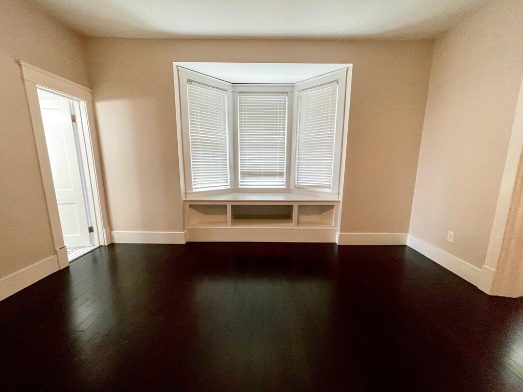 an empty room with a window and wooden floors