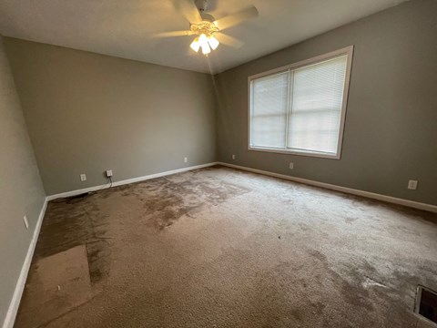 A room with a ceiling fan and a window.