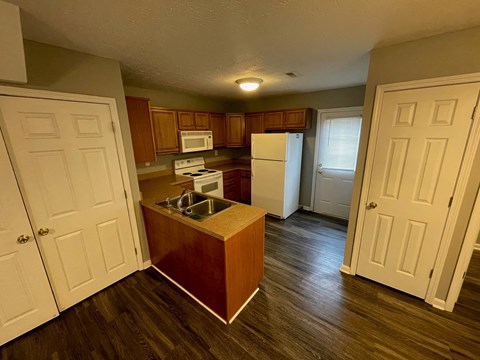 A kitchen with a white refrigerator and brown cabinets.