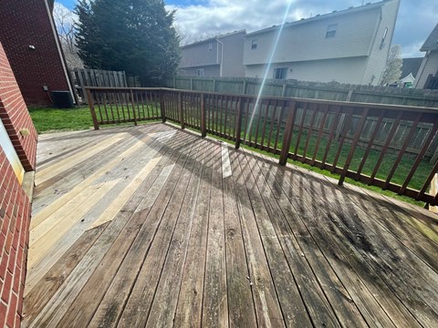 A wooden deck with a railing and a tree in the background.