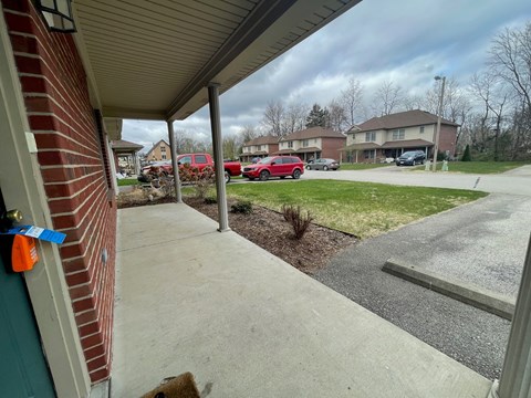 A view from a house looking out to a parking lot with cars and houses in the background.