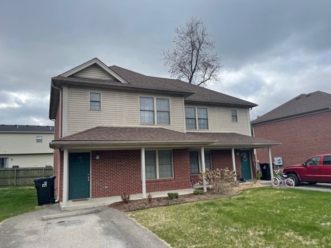 A house with a green door and a red truck parked in front.