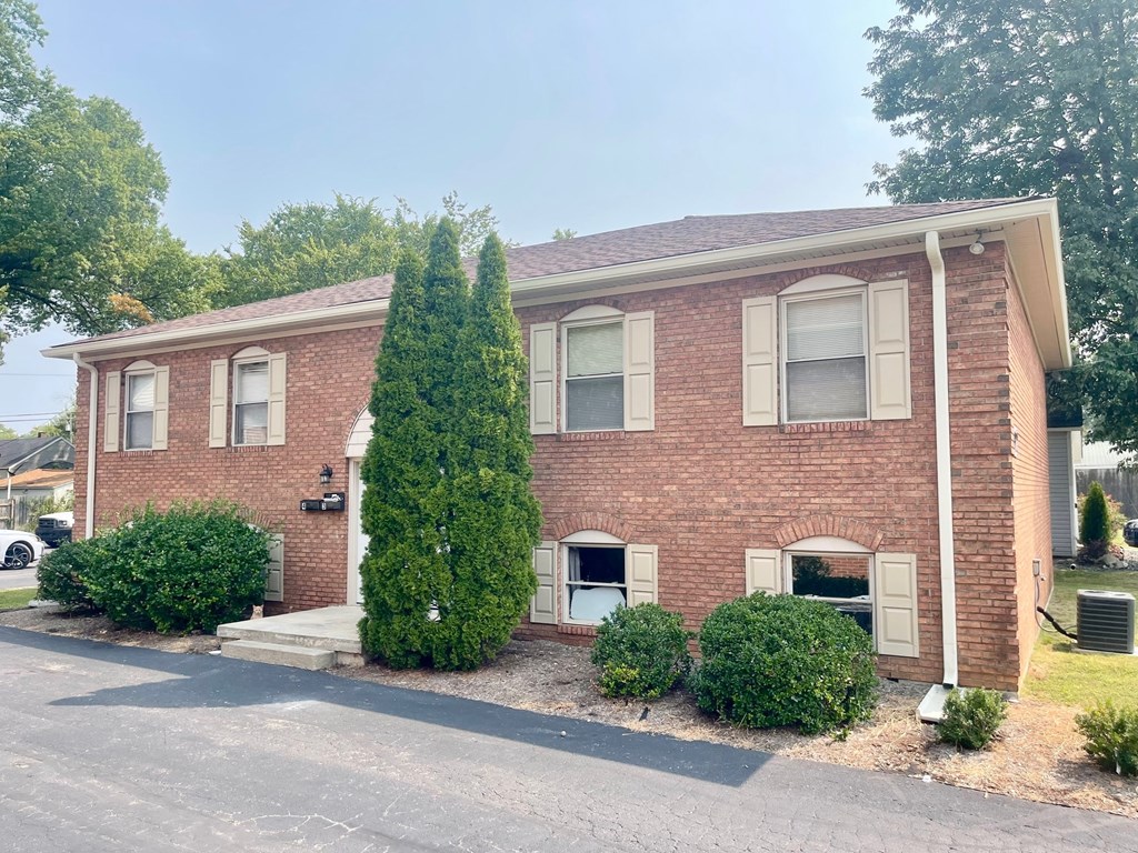 A red brick house with a tree in front.