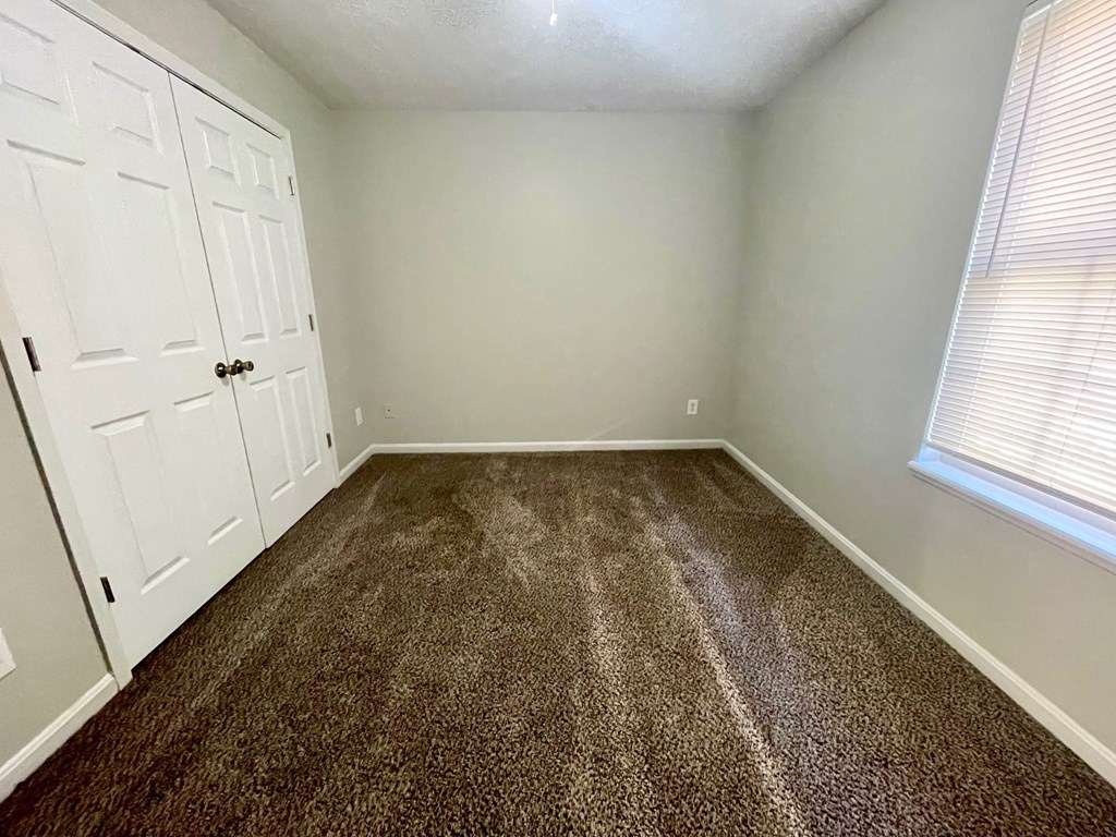 A room with a carpeted floor and a white door.