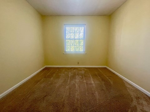A room with a window and carpeted floor.