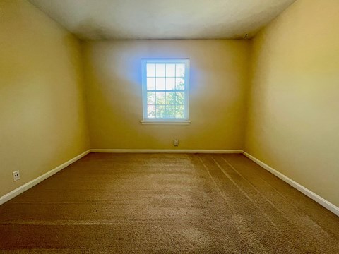 A room with a carpeted floor and a window.