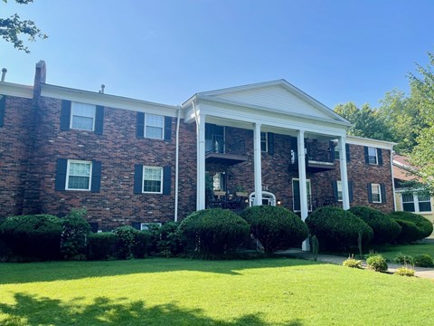 A large brick house with a white porch and black shutters.