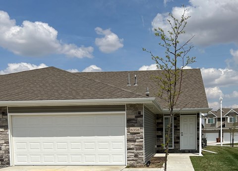 A house with a garage door and a tree in front.