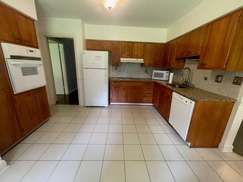 an empty kitchen with white appliances and wooden cabinets