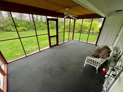 a screened in porch with a view of the grass