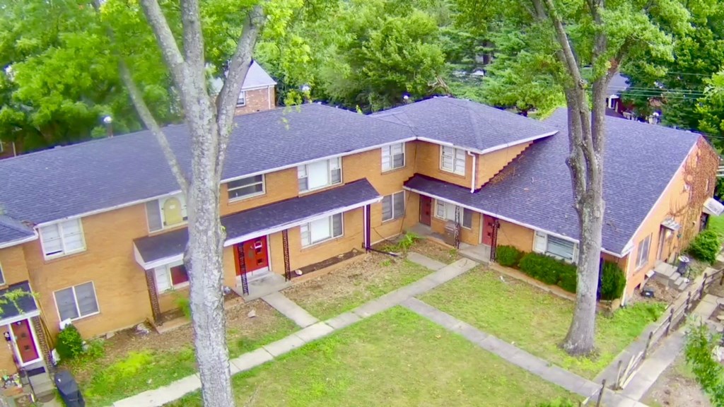 A house with a red door is surrounded by trees.