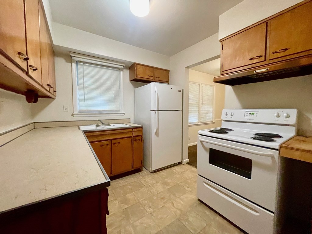 A kitchen with a white stove top oven and a white refrigerator.