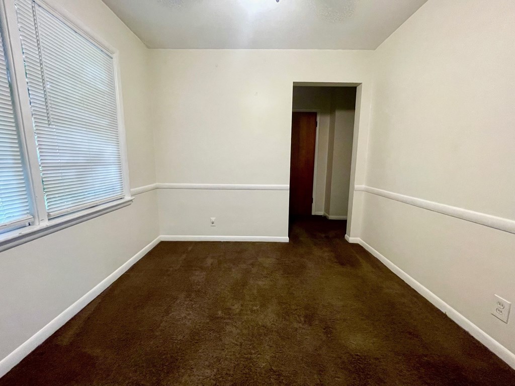 A room with brown carpet and a door at the end.