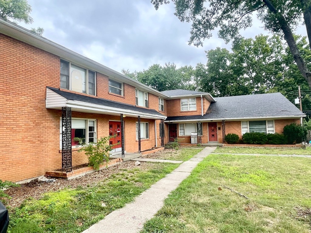A brick house with a red door and a small front yard.