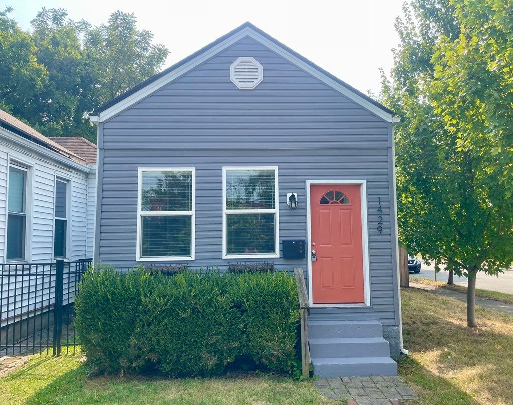 A small house with a red door and a grey exterior.