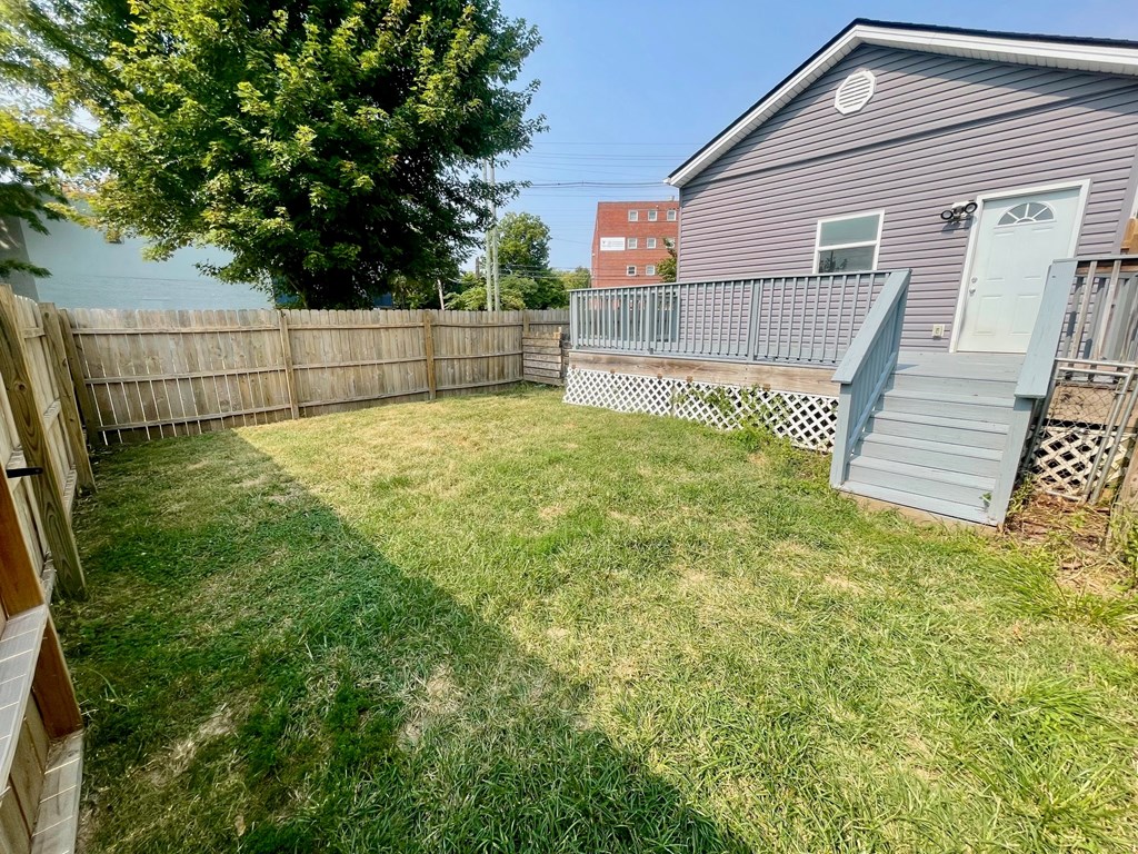 A backyard with a wooden fence and a house in the background.