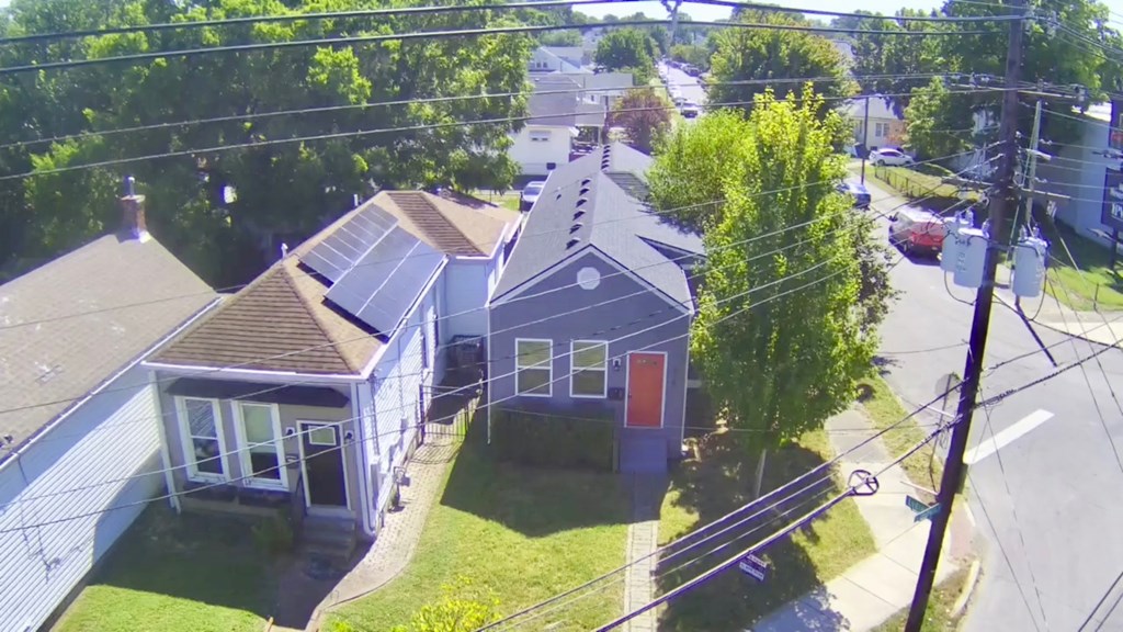 A house with a red door is surrounded by a green lawn.