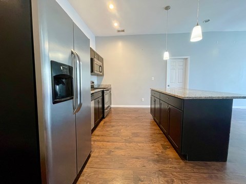 A kitchen with a stainless steel refrigerator and wooden flooring.