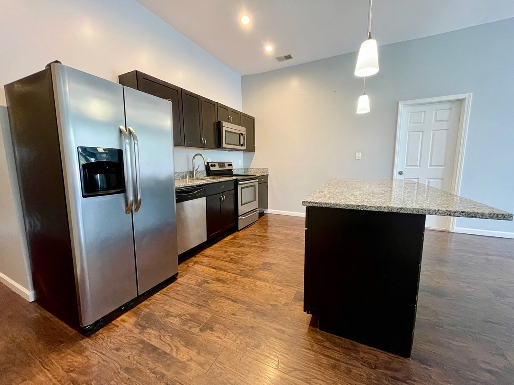 A kitchen with a refrigerator, microwave, and oven.