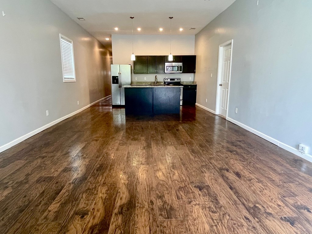 A kitchen with dark wood floors and white walls.