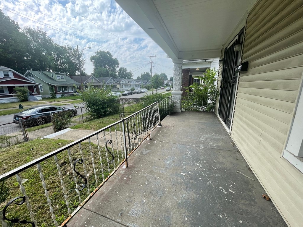 the front porch of a house with a concrete walkway and a fence