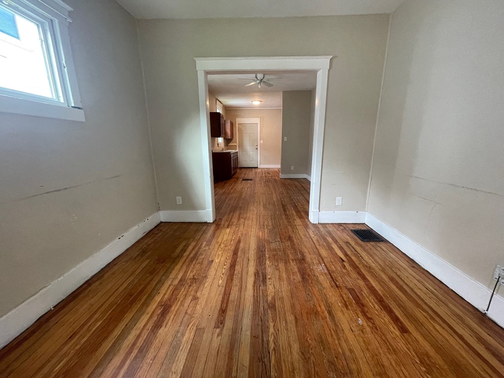 an empty living room with wood flooring and white walls