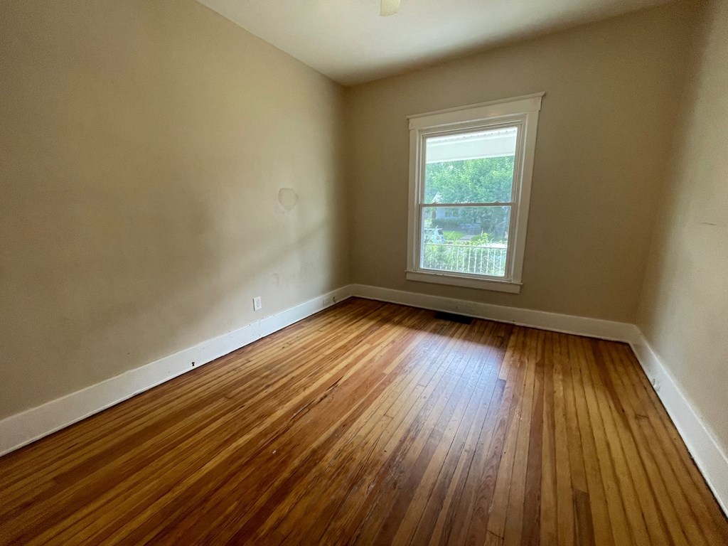 an empty room with wooden floors and a window