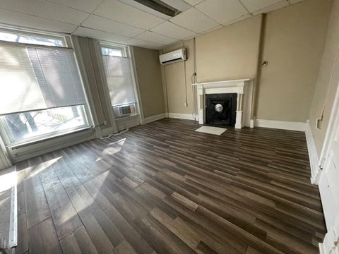 A room with a fireplace and wood flooring.