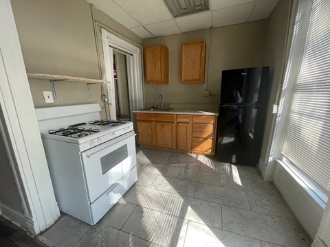 A kitchen with a white gas stove and black refrigerator.
