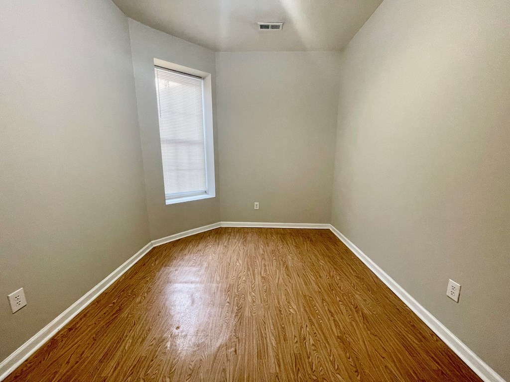 an empty room with wood floors and a window