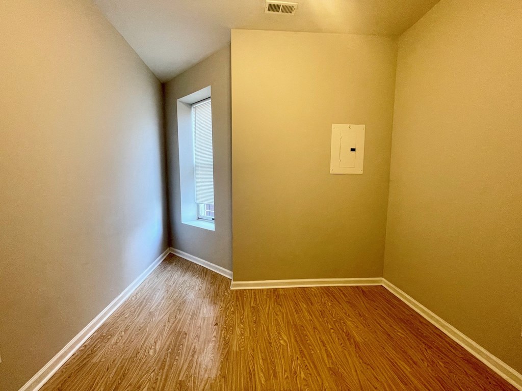 the bedroom of a home with wood flooring and a window