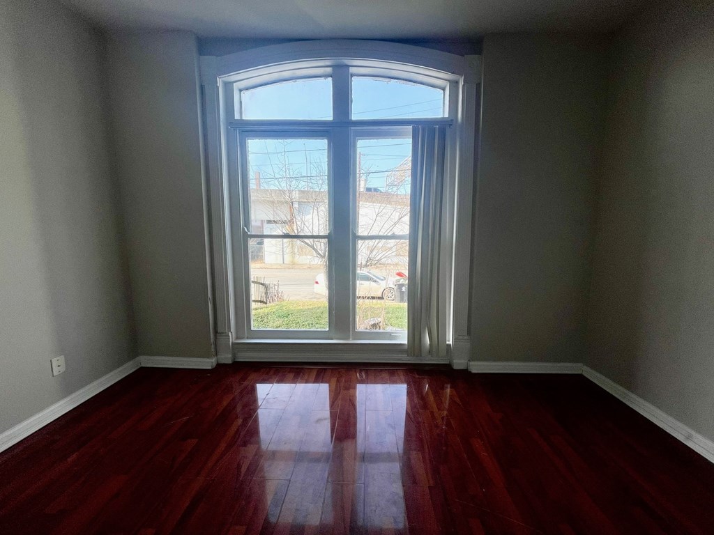 a living room with a large window and wooden floors