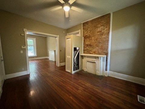 an empty living room with a fireplace and a ceiling fan