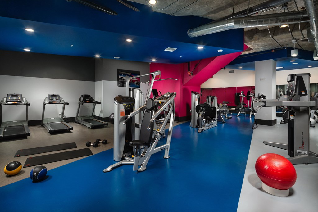 a gym with various exercise equipment and a red wall