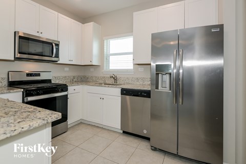 A kitchen with a stainless steel refrigerator and a granite countertop.