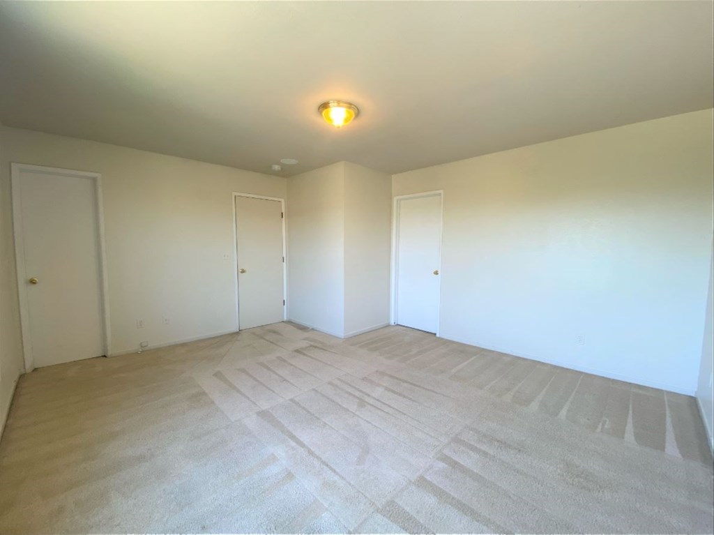the living room of an empty home with white walls and flooring