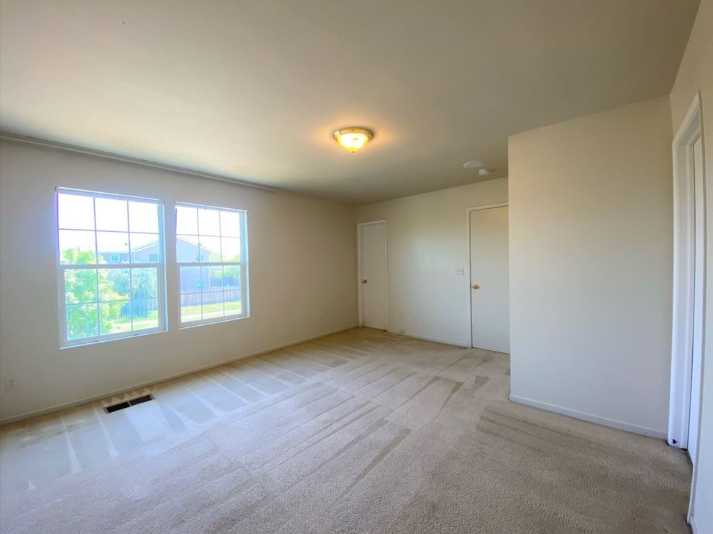 the living room and dining room of an empty home with white walls and flooring