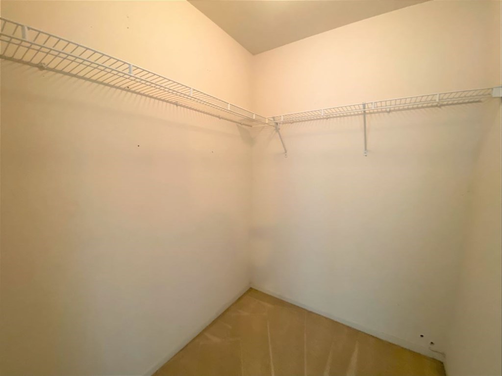 an empty room with white walls and a wire rack on the wall