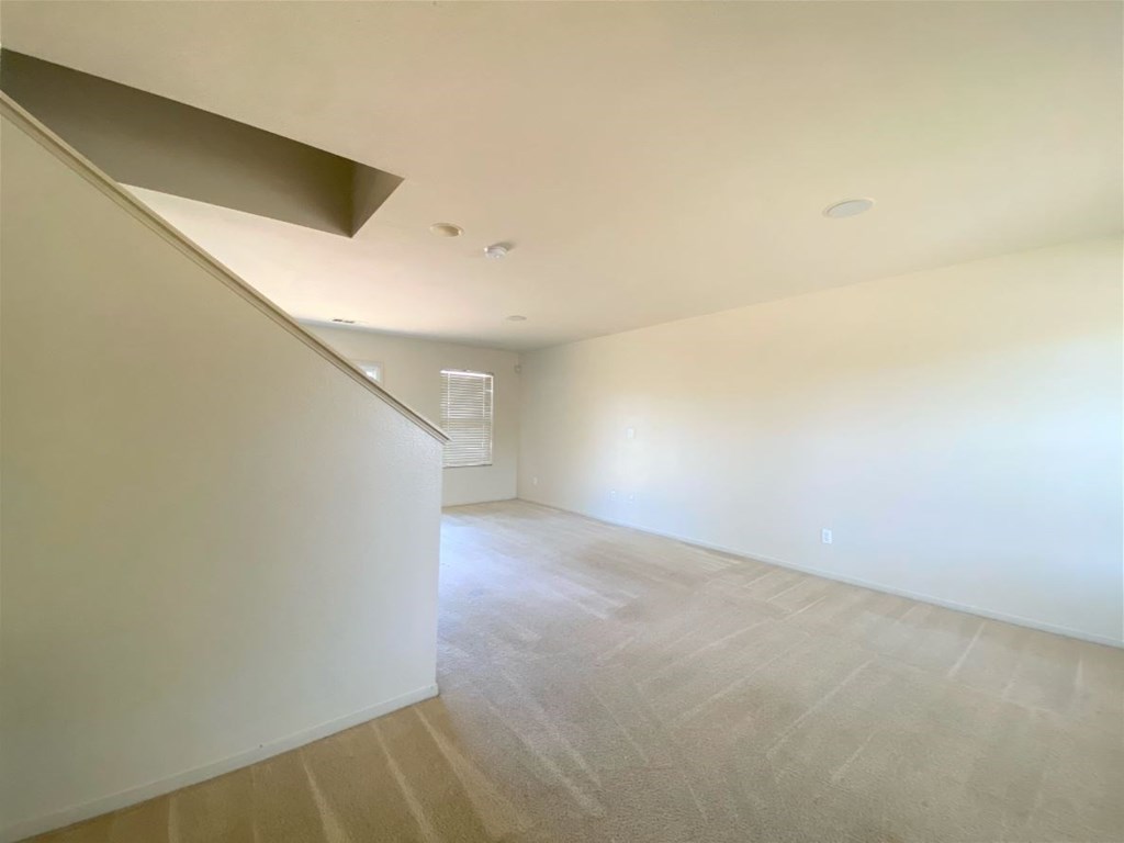 the living room and dining area of a house with white walls and flooring