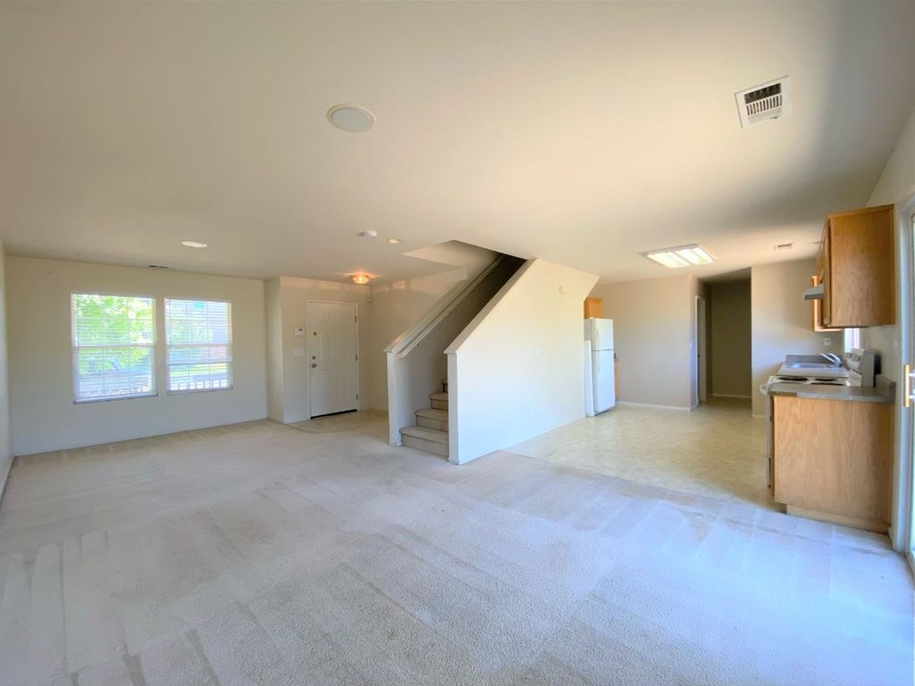 an empty living room with a staircase in the middle
