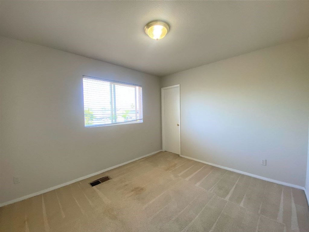 the living room of an empty home with white walls and a window