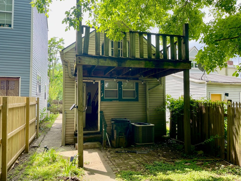 A small house with a wooden deck is surrounded by a wooden fence.