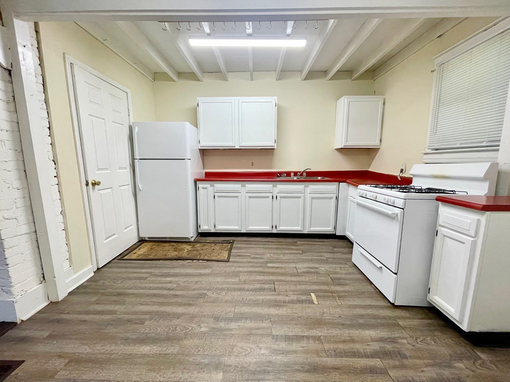 A kitchen with white appliances and wooden floors.
